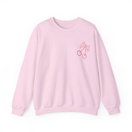 Light pink crewneck sweatshirt with a red hand-drawn Valentine’s Day collage graphic on the back, featuring hearts, bows, cherries, love notes, and a personalized love letter with initials.