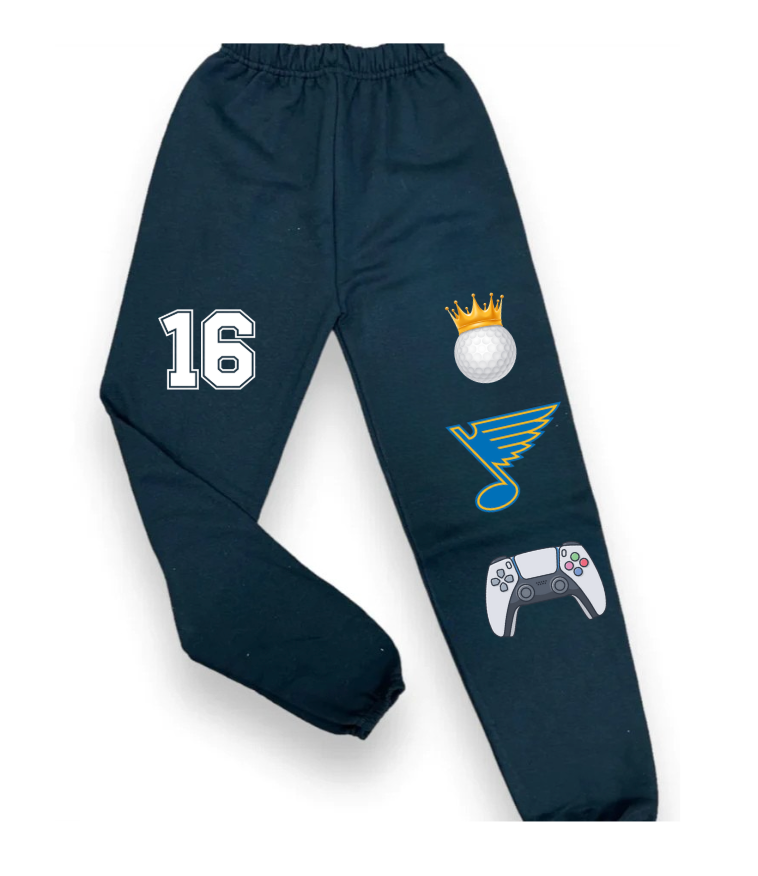 Custom favorite things sweatpants with sports number 16, golf ball with crown graphic, hockey logo, and video game controller on black pants.